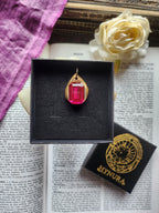 Colgante de bronce hecho a mano con cristal fucsia.