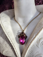 Colgante de bronce artesanal con cristal fucsia: joyería gótica única.