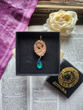 Medallón romano de bronce hecho a mano con cristal azul océano.